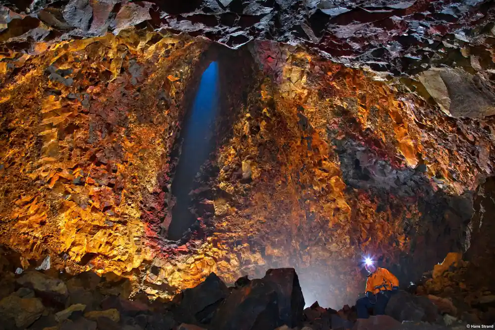 The chamber wall in orange and red with a lamp far below