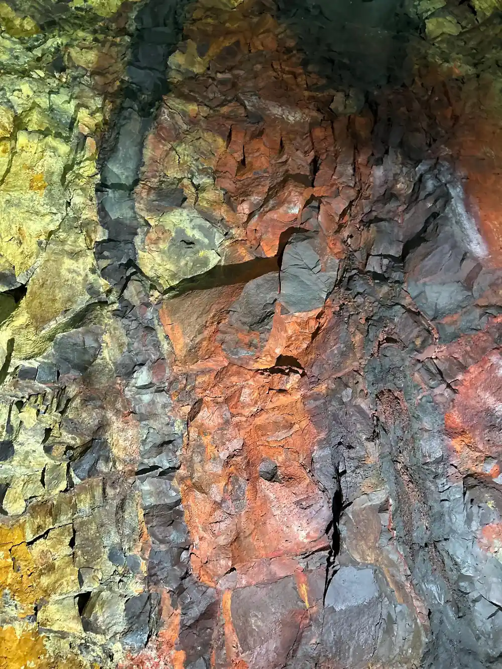 A close view of the chamber wall, red and yellow mineral staining on basalt