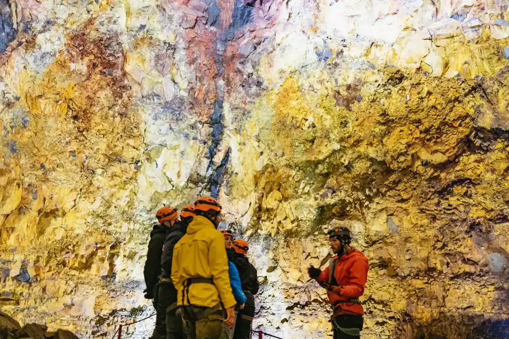 A group on the chamber floor under enormous streaked walls