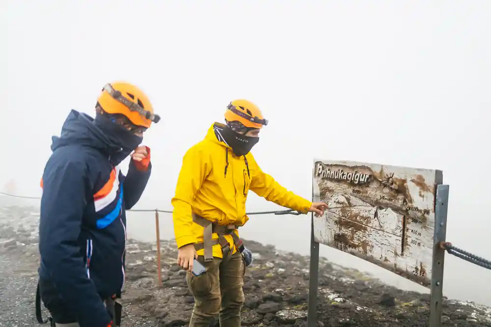 A guide pointing at the Thrihnukagigur information board in thick fog