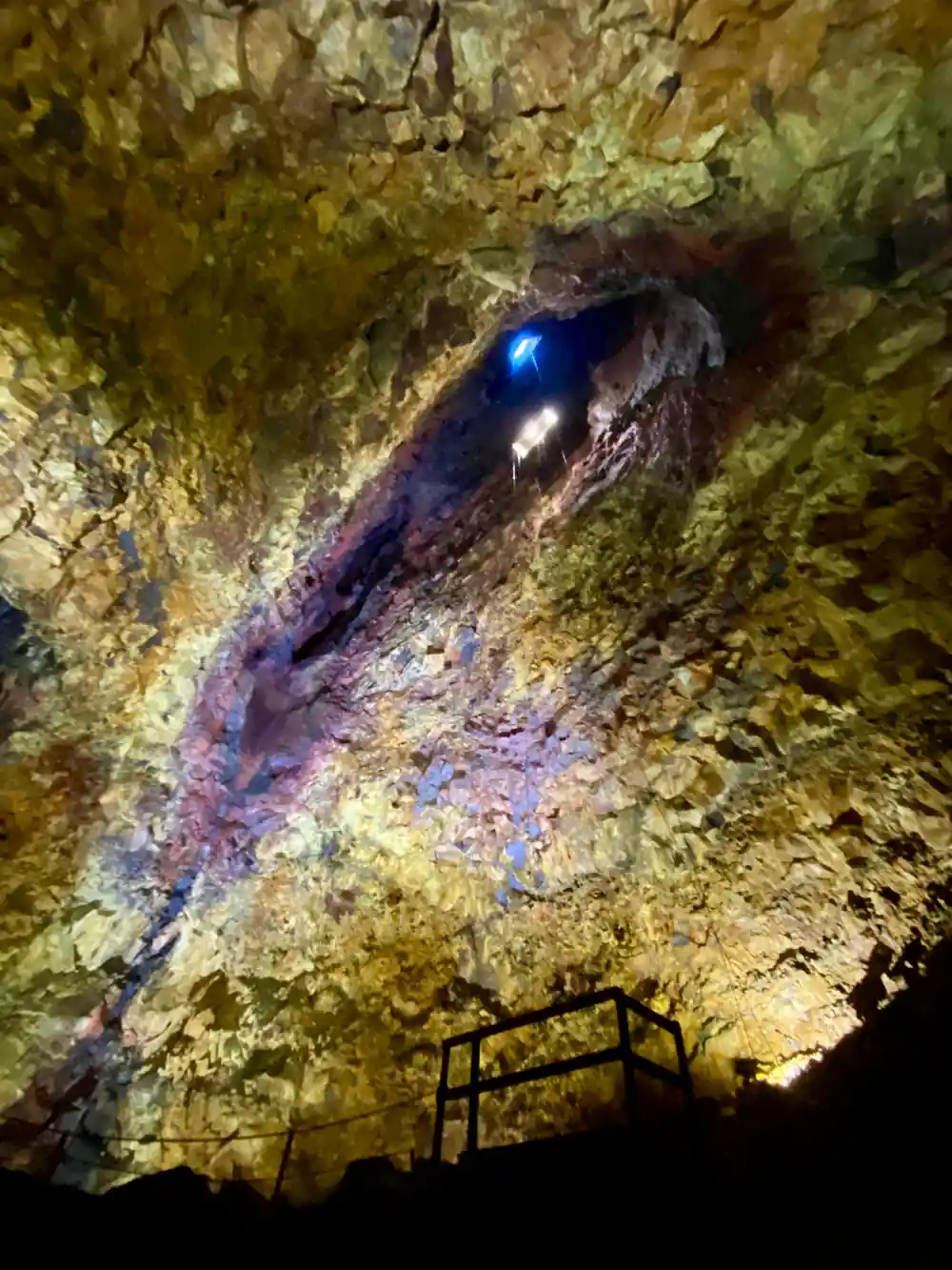 A lamp set into the chamber wall among yellow and violet rock