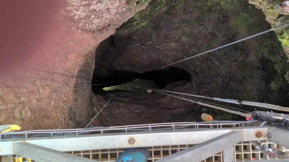 The lava-tube mouth beside the walkway at the crater