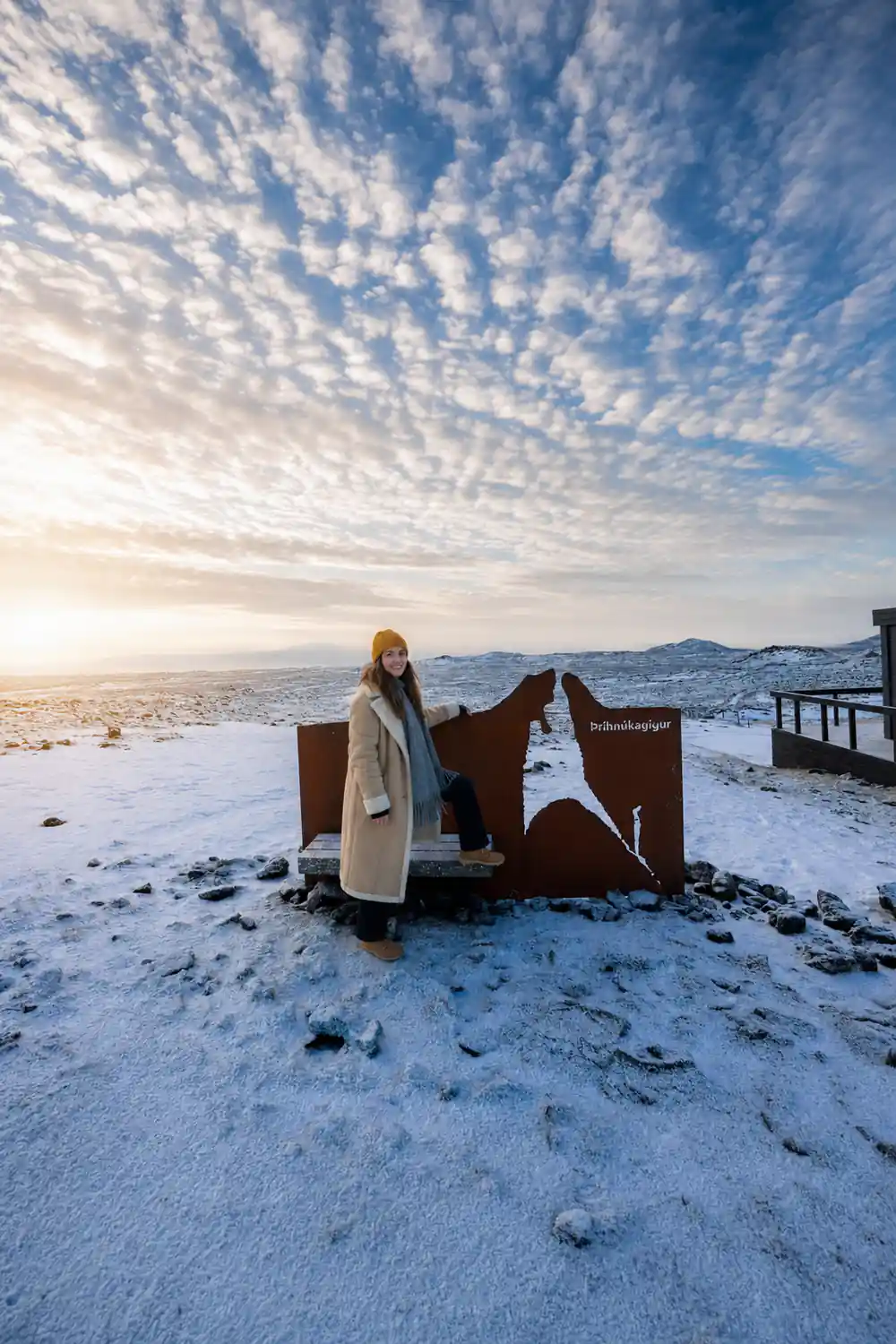 A visitor at the Thrihnukagigur signpost on snow-covered lava